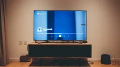Černá plochá televize na hnědém dřevěném stojanu